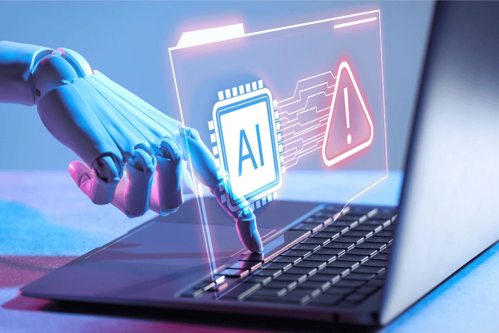 A robotic hand types on a laptop keyboard.